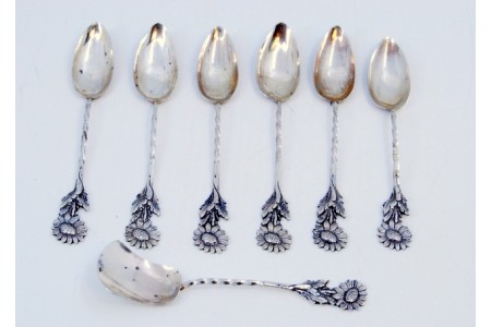 Conjunto de seis colheres de café e pá de açúcar com malmequeres e cabos torcidos.